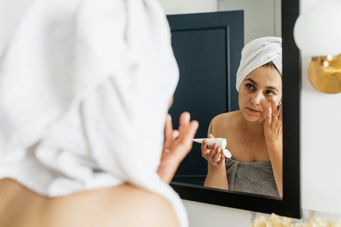 a woman doing a face mask in the mirror