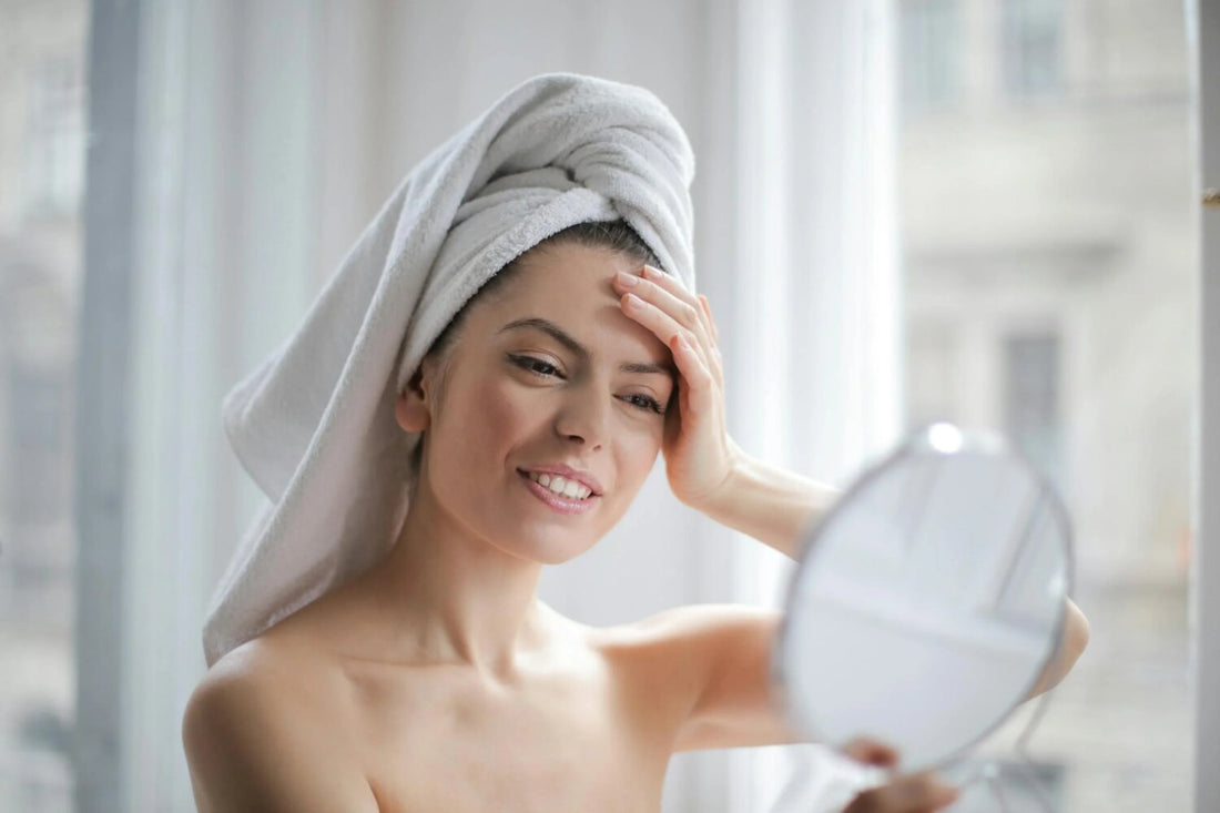 a woman with a towel on her head looking in a mirror