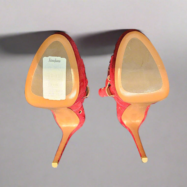 Red high-heeled shoes with gold soles on a gray background