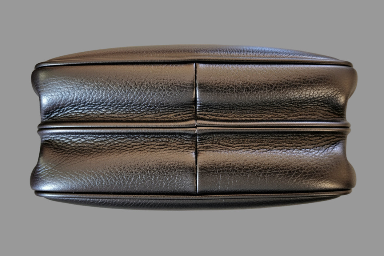 Black leather handbag bottom on a reflective surface with a neutral background