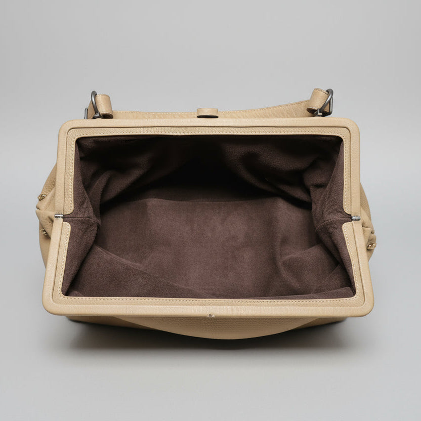 Beige handbag with brown interior on a gray background