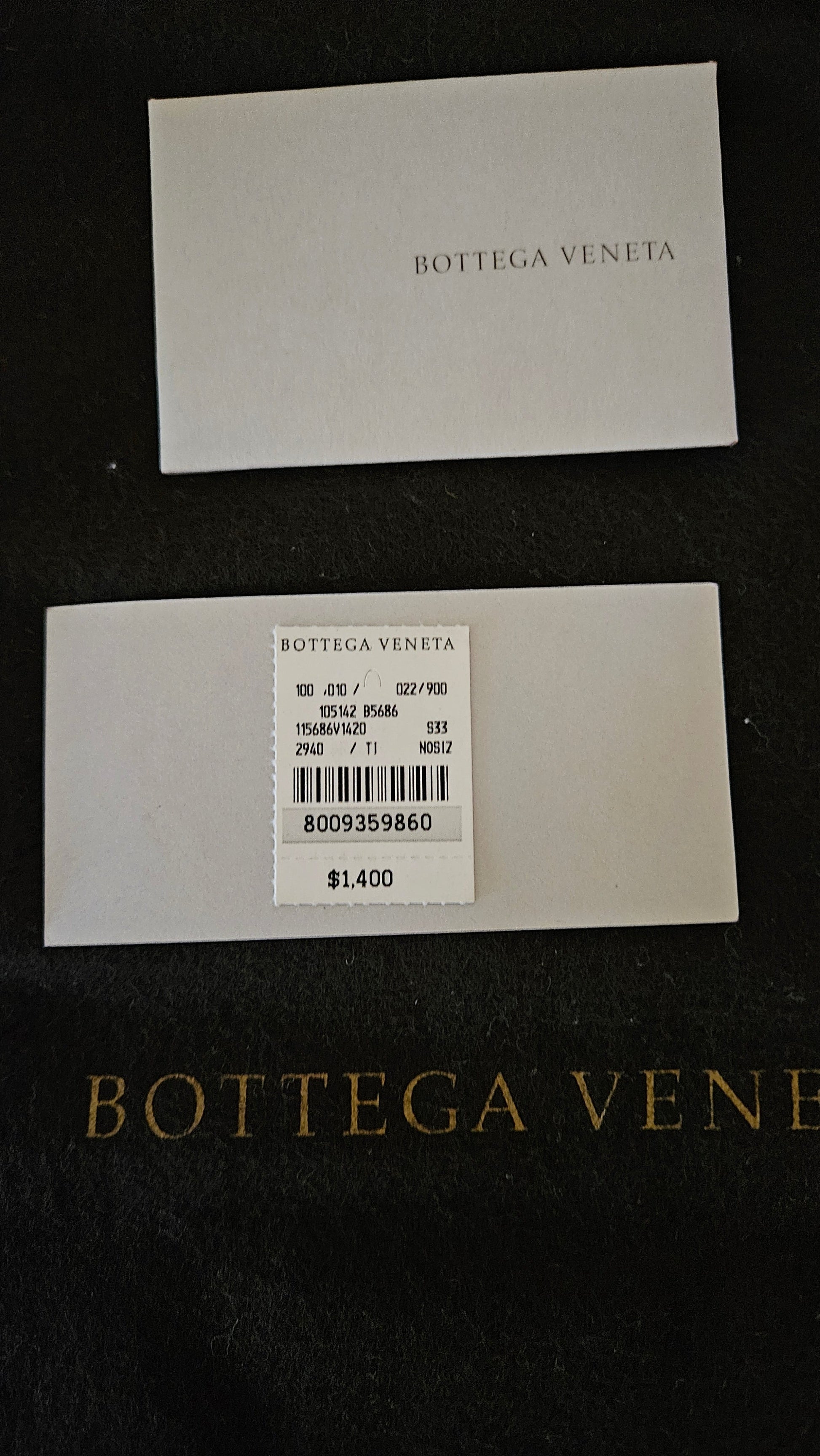 Two white labels with Bottega Veneta branding on a dark background