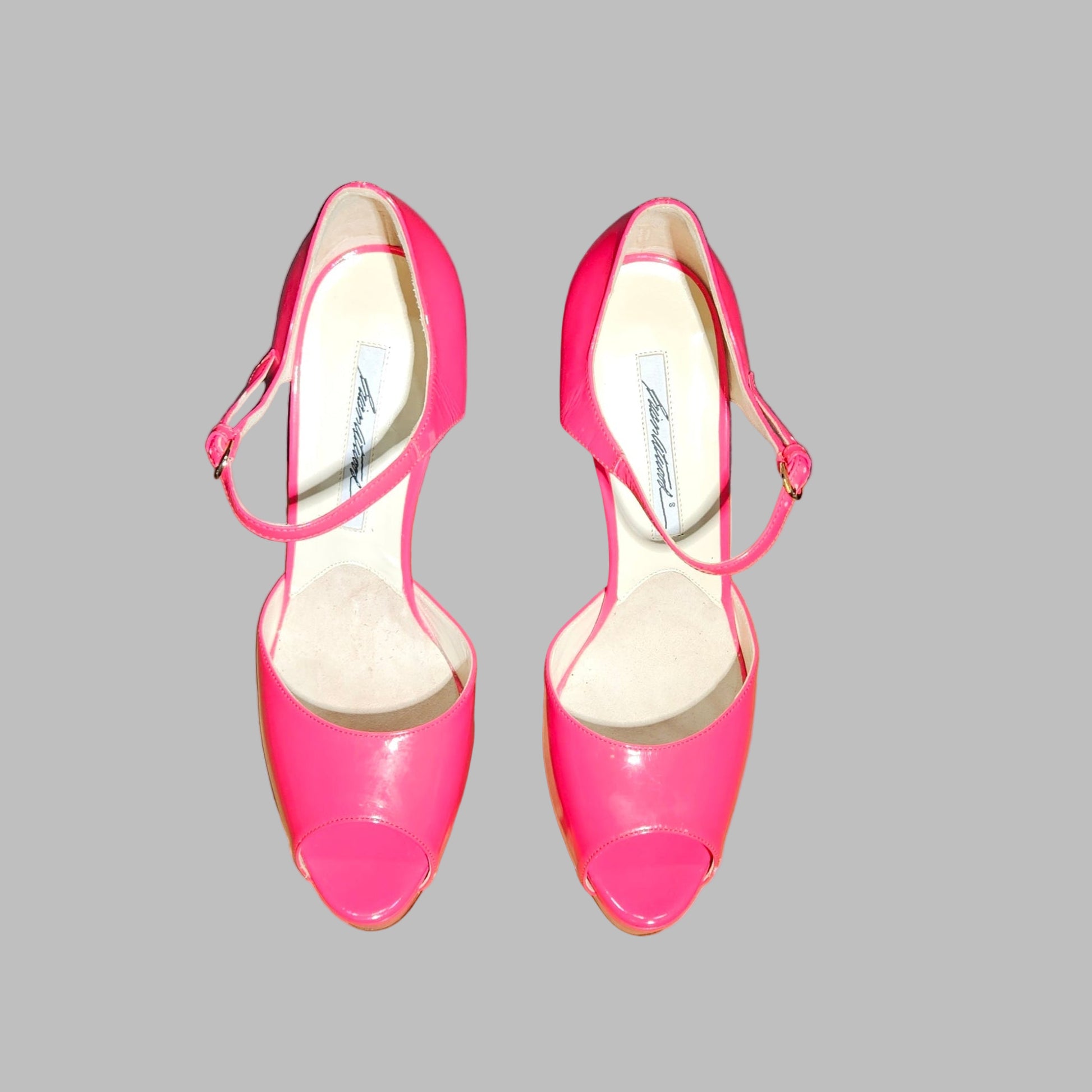 Pair of bright pink high-heeled shoes on a gray background