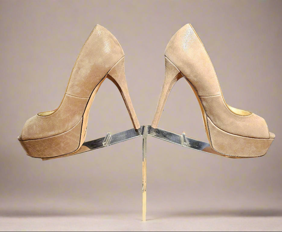 Pair of beige high-heeled shoes on a clear stand with a dark background