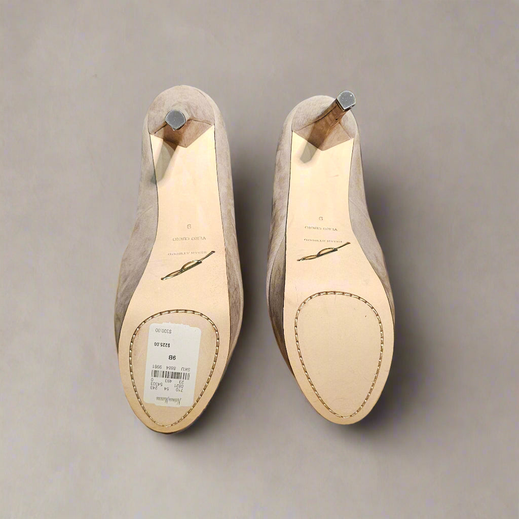 Pair of beige shoes with soles facing up on a gray background