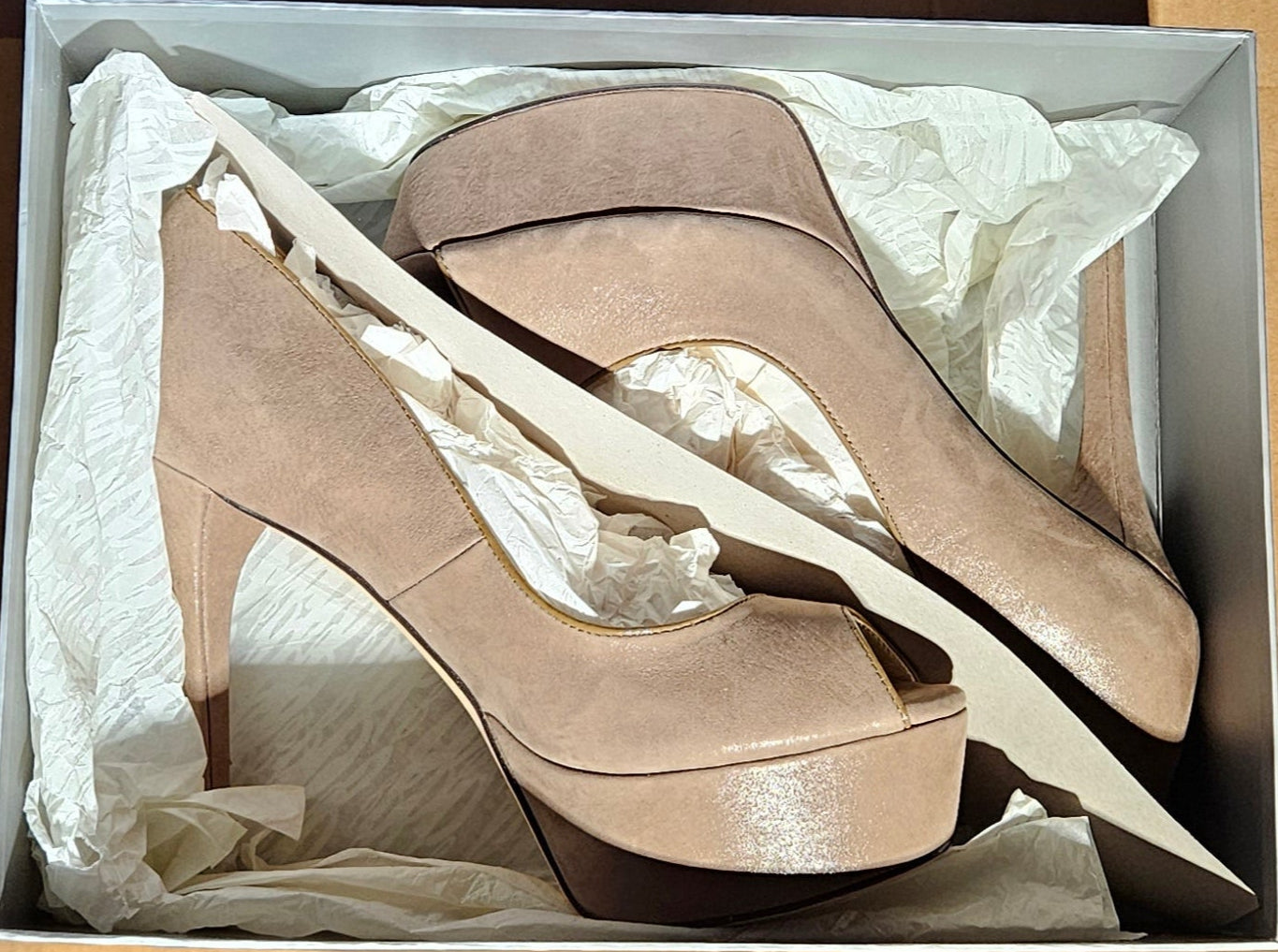 Pair of high-heeled shoes in a cardboard box on a dark surface