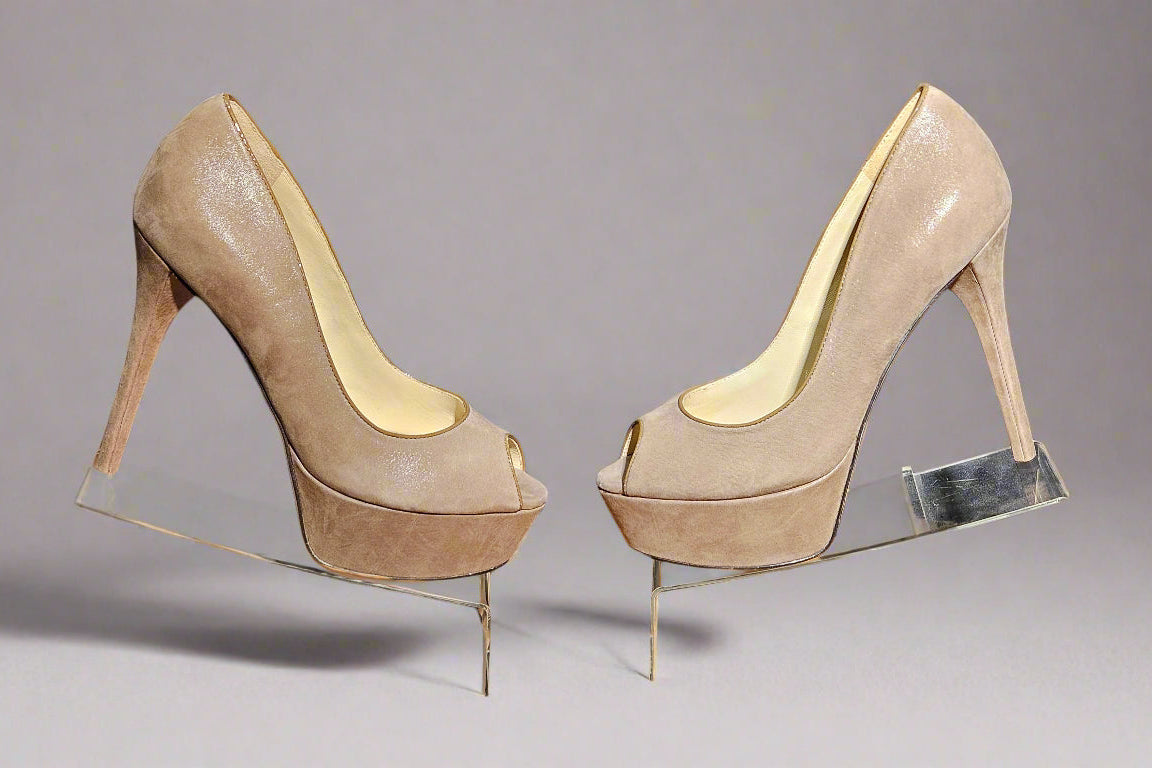 Pair of beige high-heeled shoes on a clear stand against a dark background