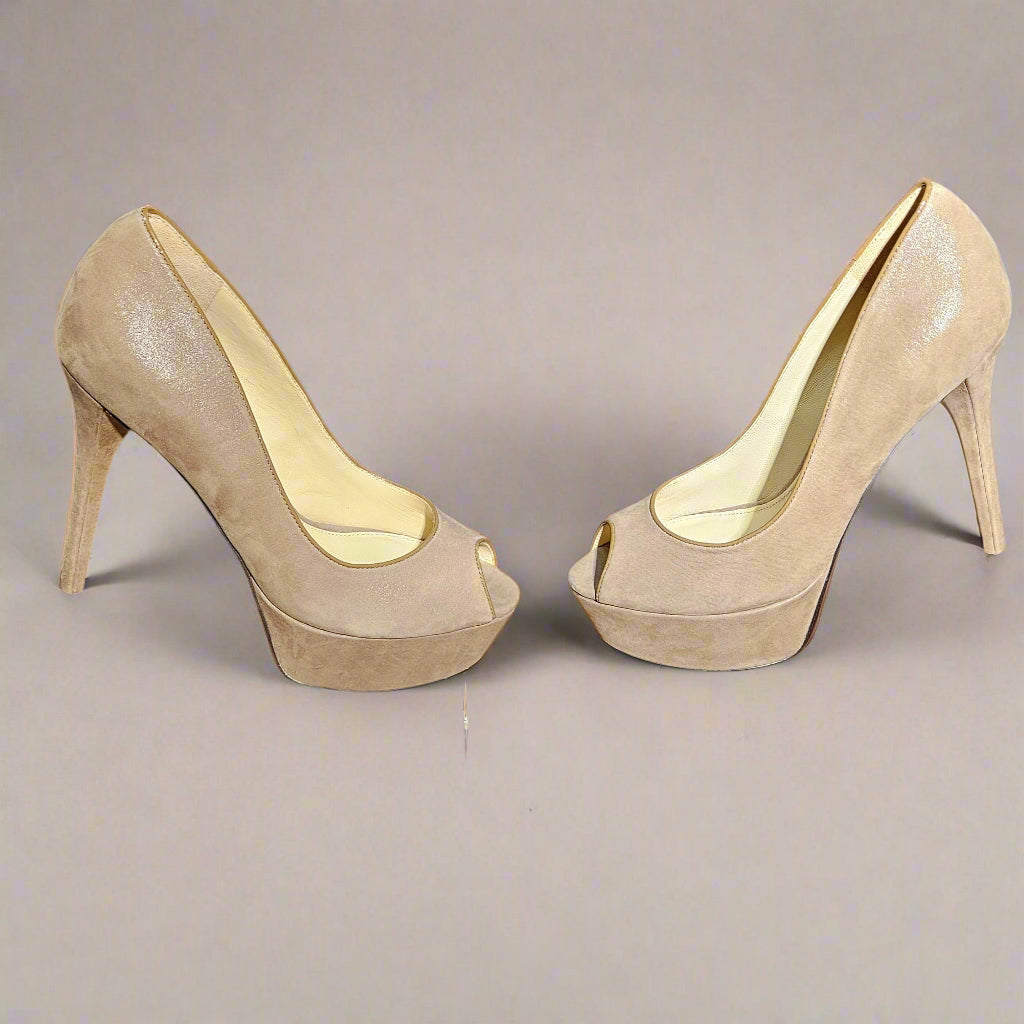 Pair of beige high-heeled shoes on a clear stand with a dark blue background