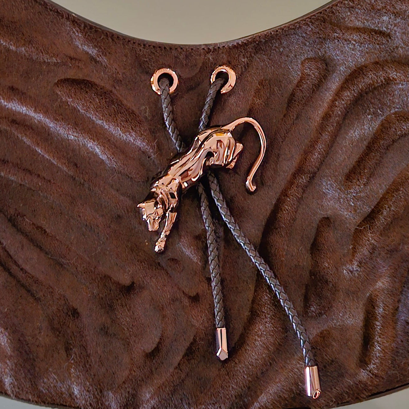 Brown textured bag with a strap and gold panther toggle