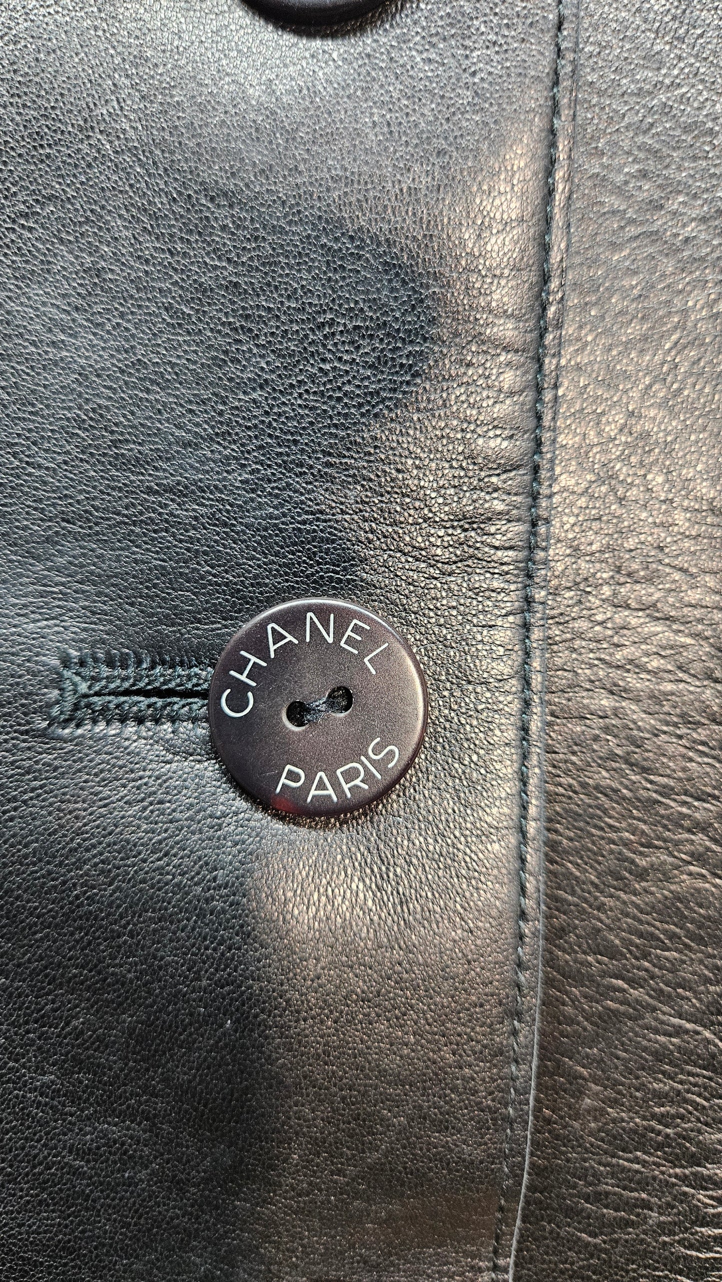 Close-up of a Chanel button on a black leather surface