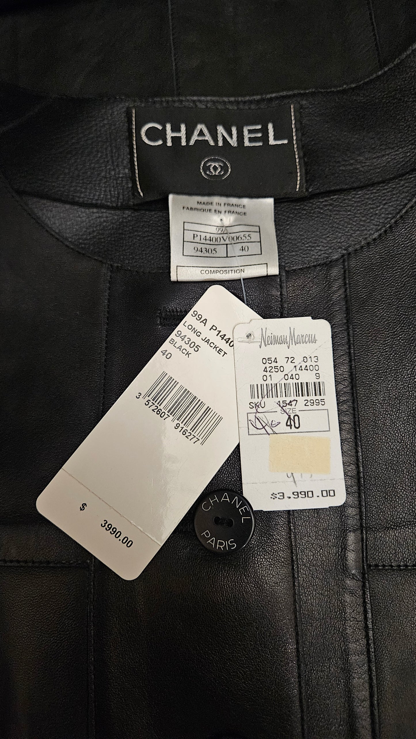 Close-up of a Chanel label on a black garment with tags attached.