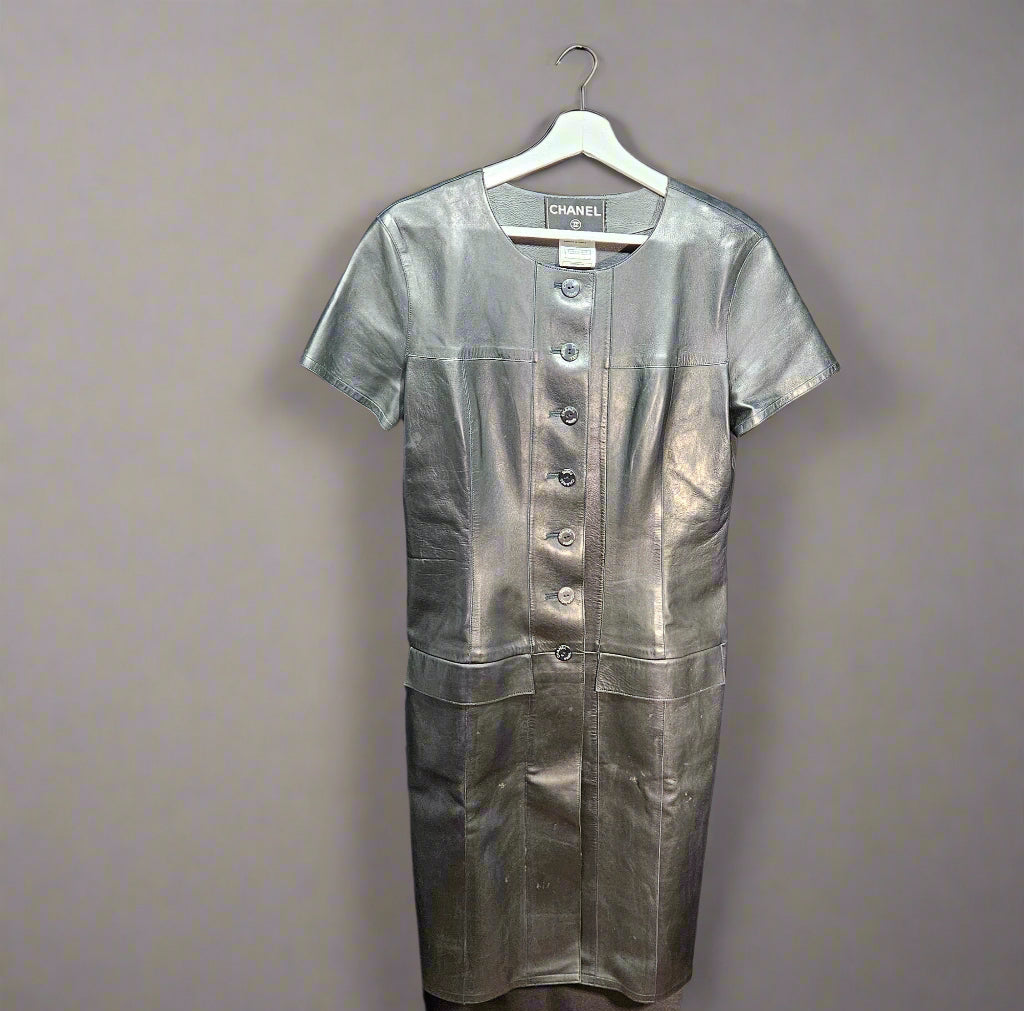 Black leather dress on a hanger against a plain background