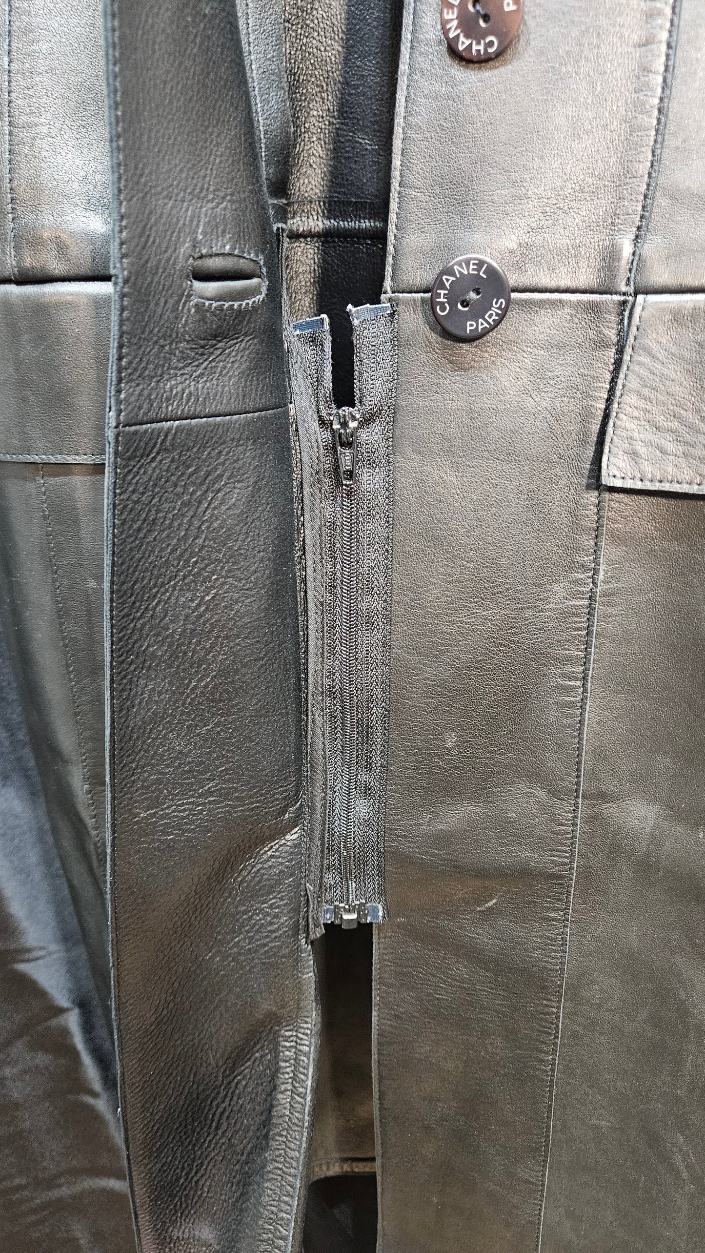 Close-up of a gray leather jacket with buttons and zipper