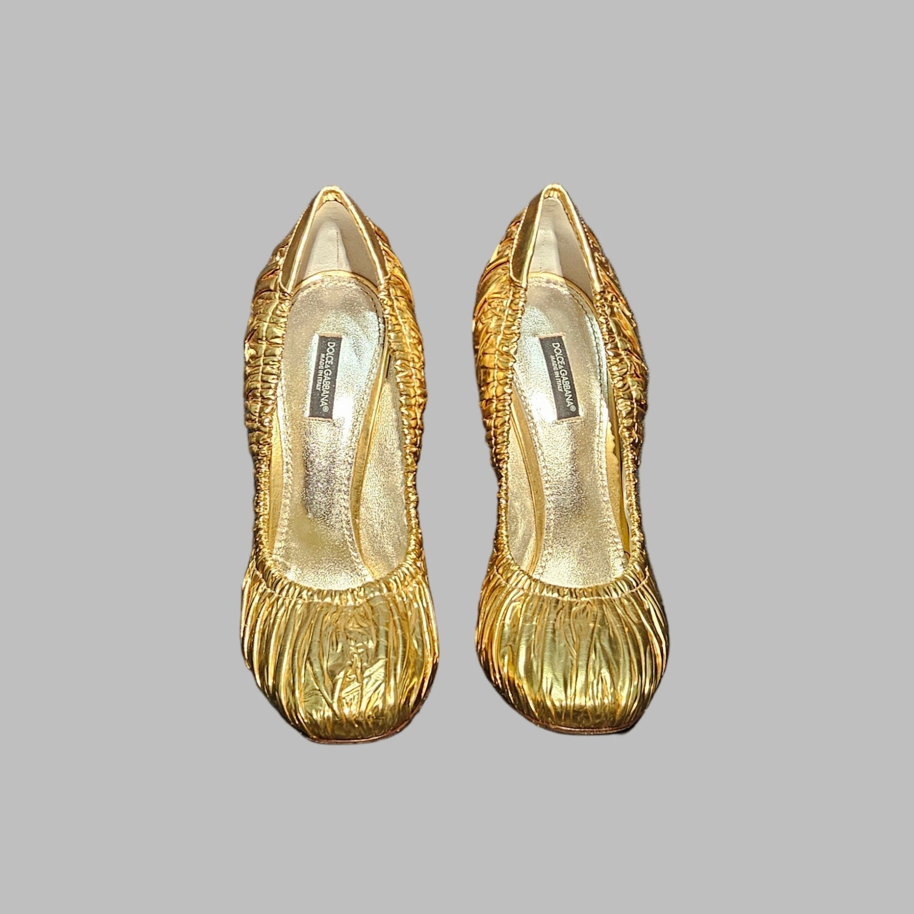 Pair of gold shoes on a gray background