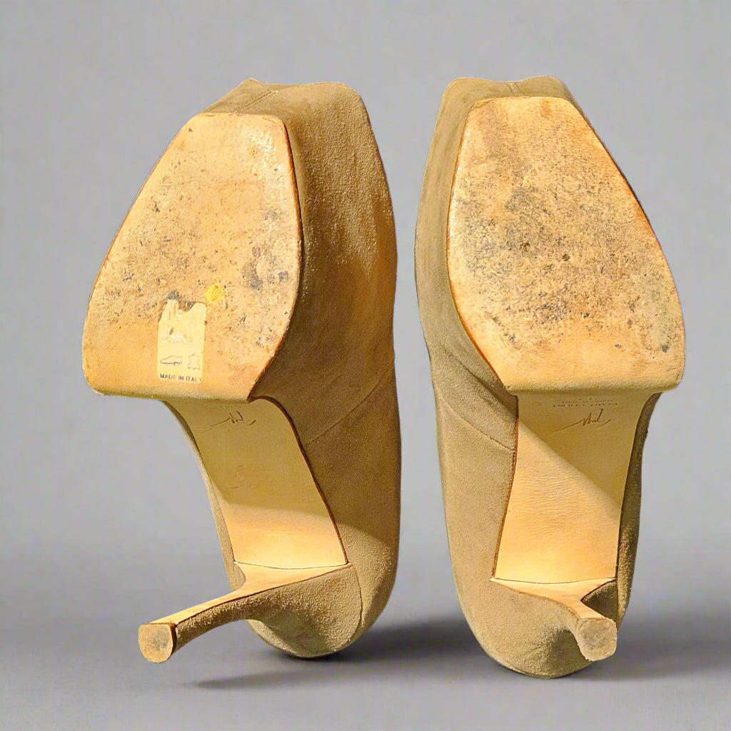 Pair of worn high-heeled shoes on a gray background