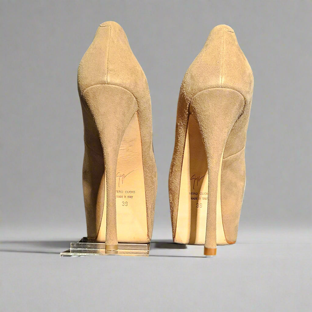Pair of beige high-heeled shoes on a clear stand against a gray background