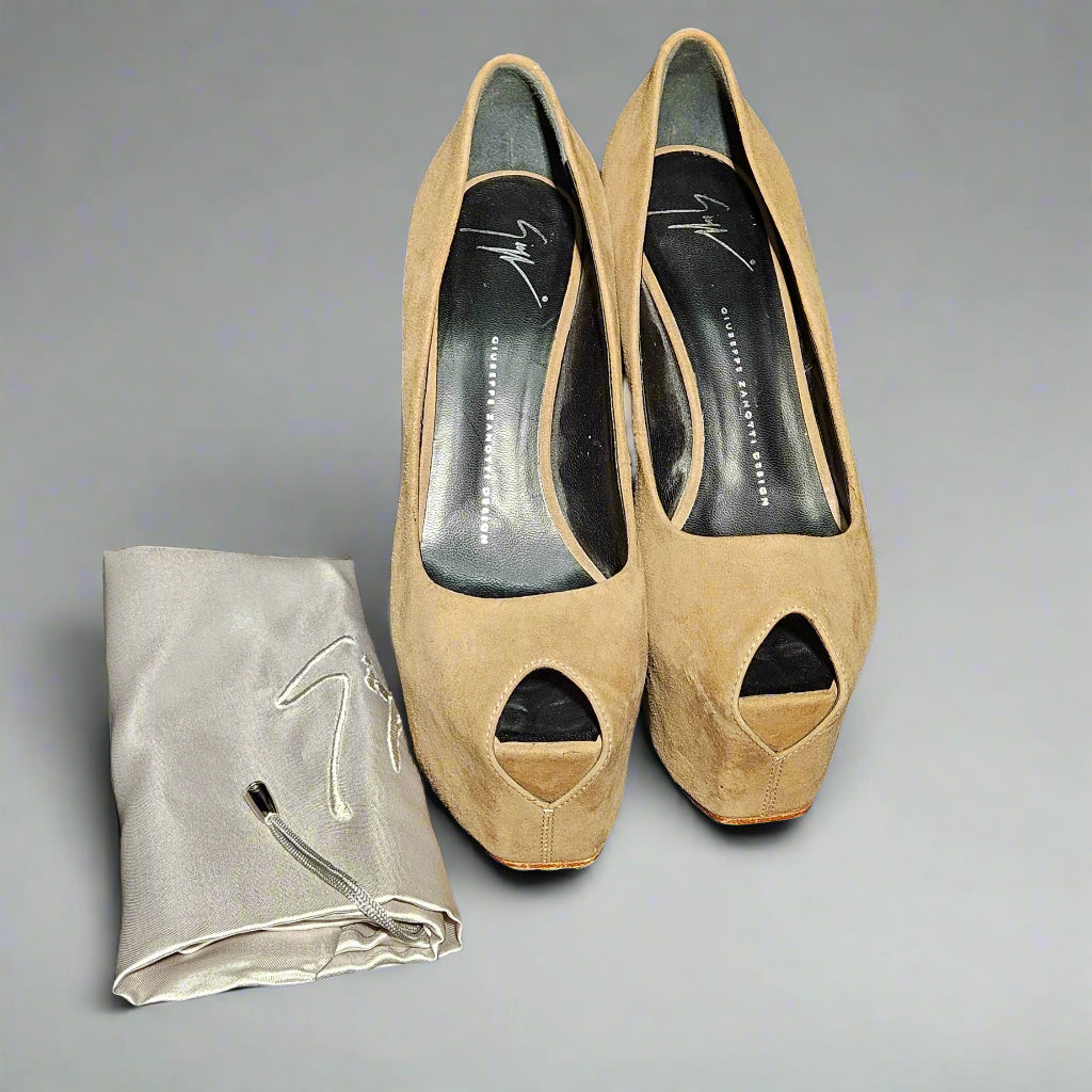 Pair of beige high-heeled shoes with open toes on a dark fabric background