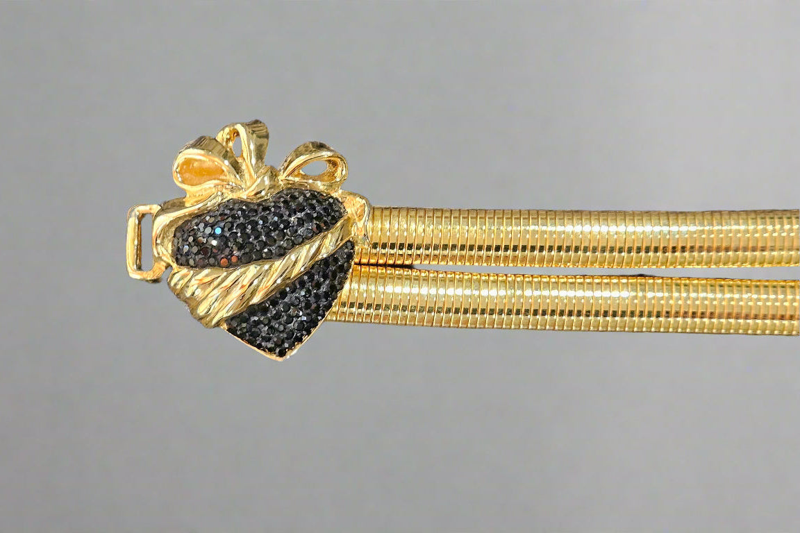Gold heart buckle with black gemstones on a gray background