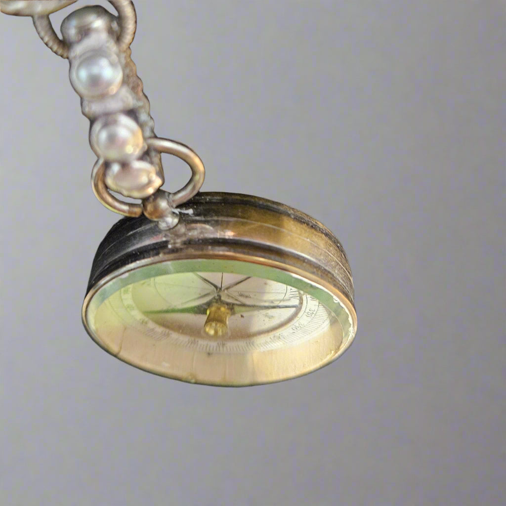 Close-up of a decorative pendant with a compass design on a gray background