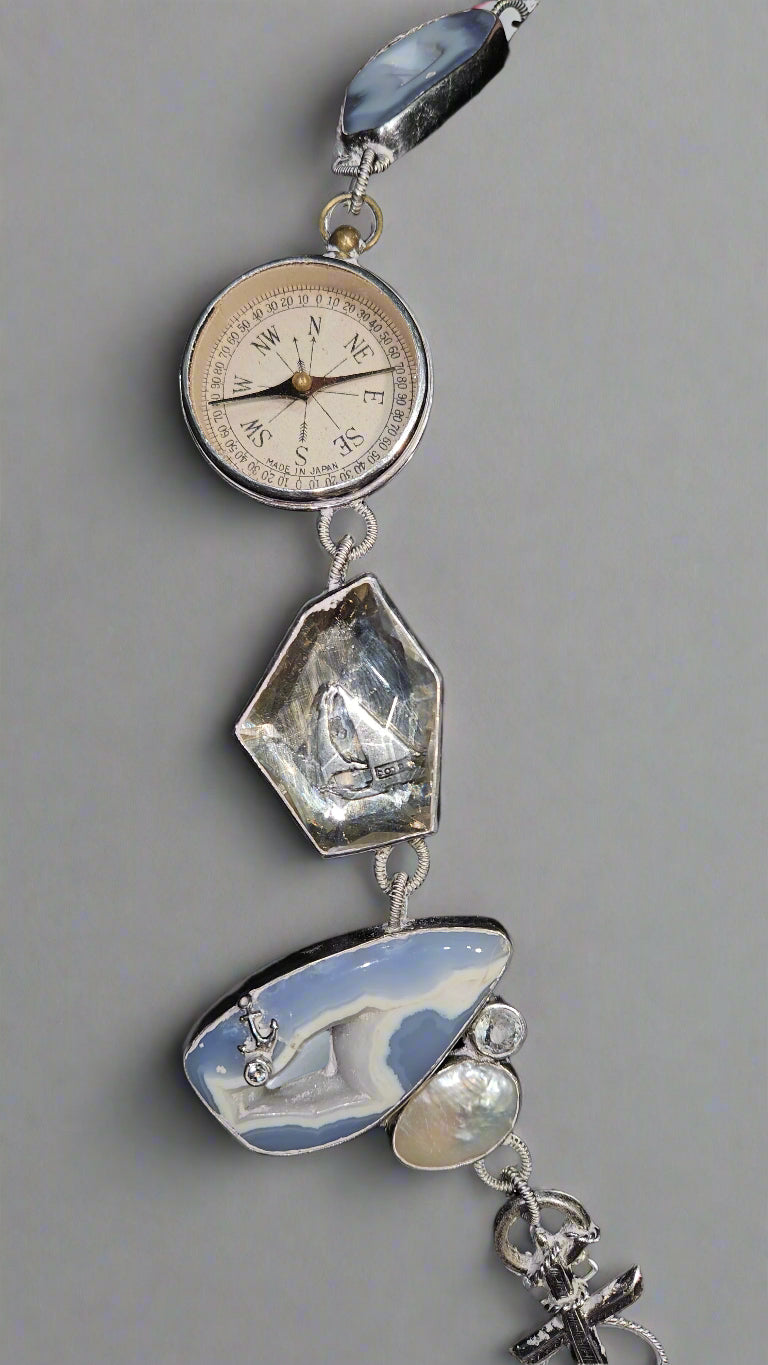 Decorative pendant with clock face, stones, and charms on a gray background