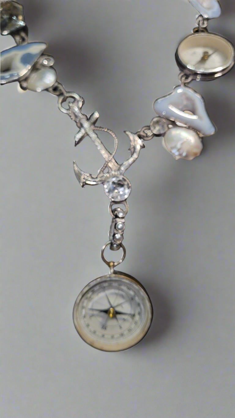 Jewelry with anchor and compass charm on a dark background