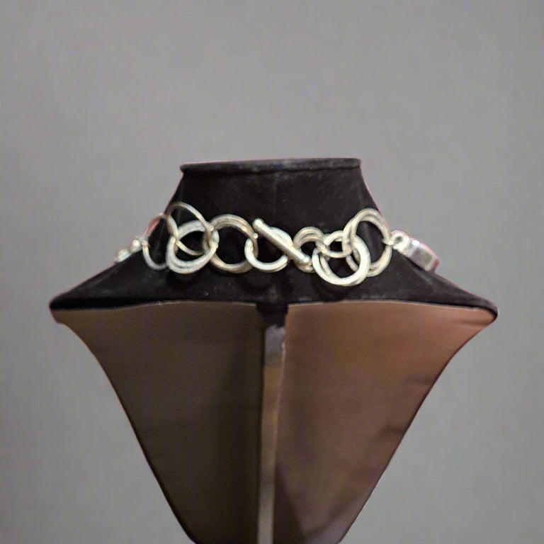 Silver chain necklace on a black mannequin bust against a gray background