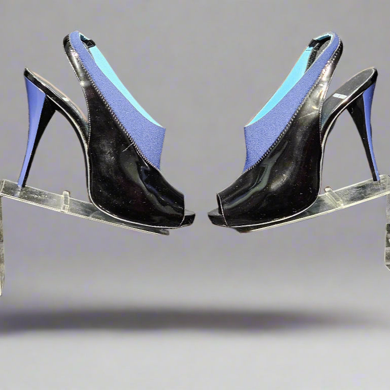 Black high-heeled shoes with blue soles on a clear stand against a gray background