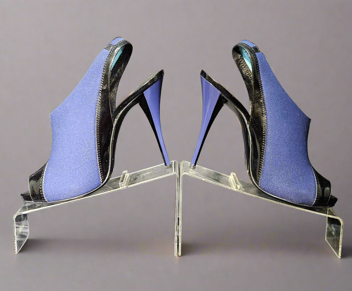 Pair of blue high-heeled shoes on a clear stand against a gray curtain background