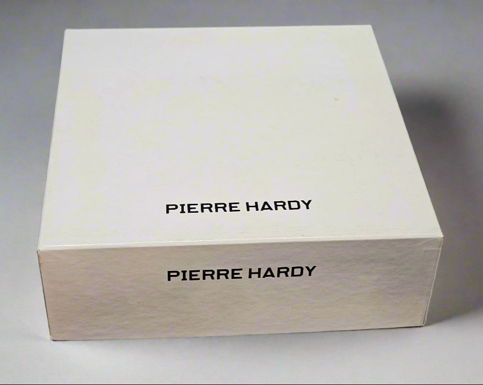 White box with 'Pierre Hardy' branding on a black fabric background