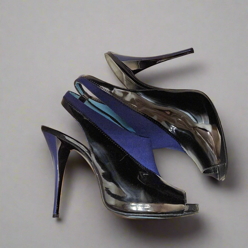 Pair of black high-heeled shoes in a box on a gray fabric background