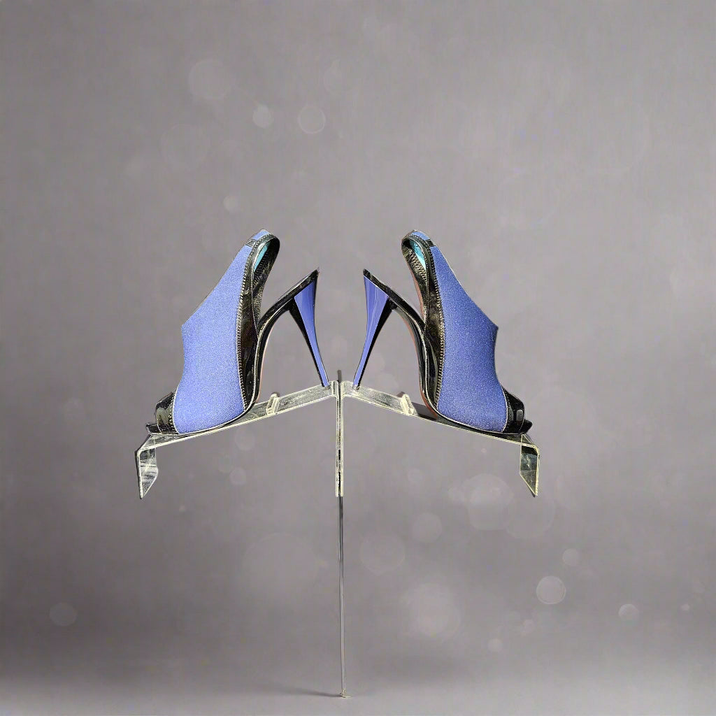 Blue high-heeled shoes on a clear stand against a gray curtain background