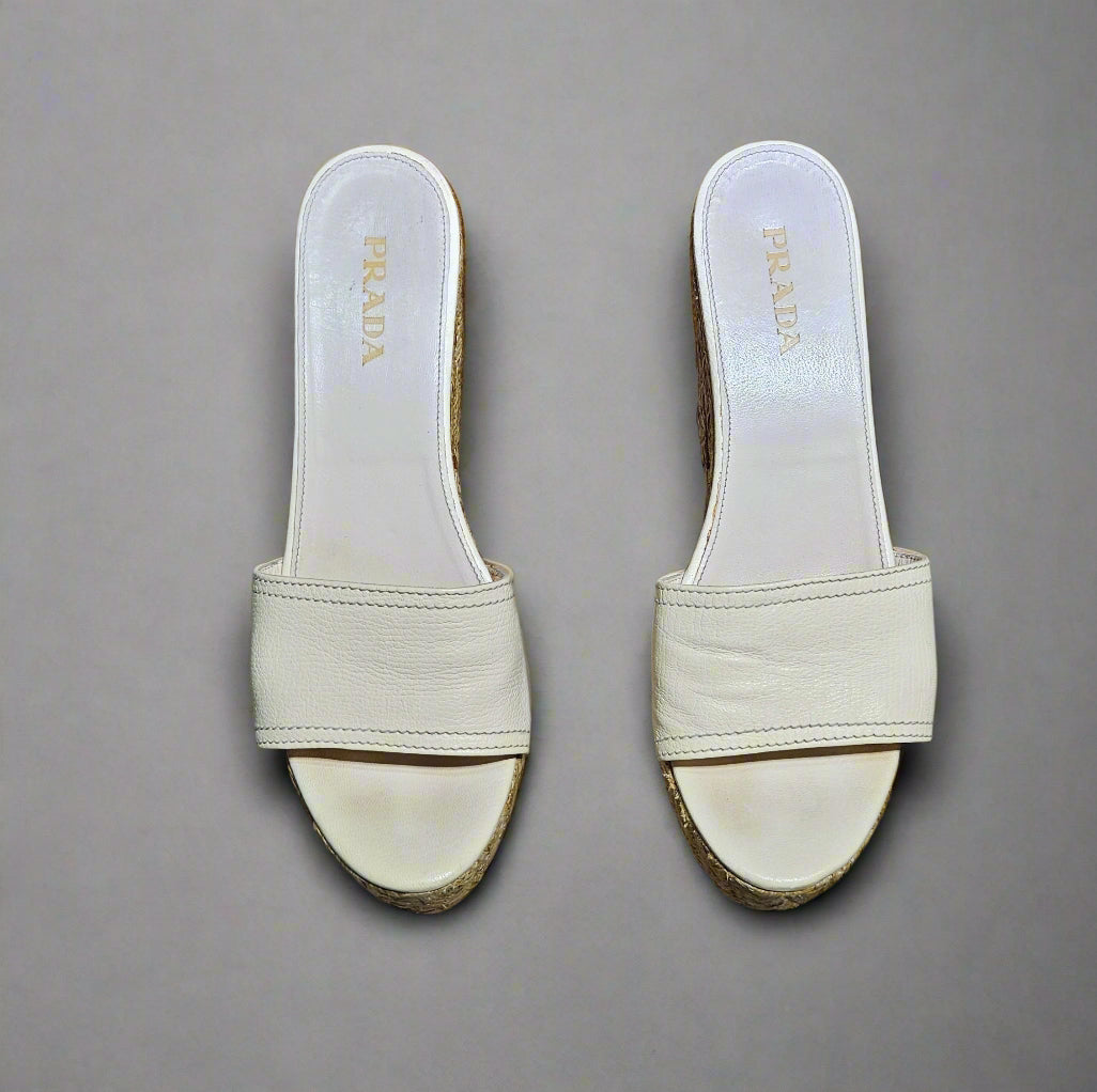 Pair of light-colored Prada slides on a marble surface