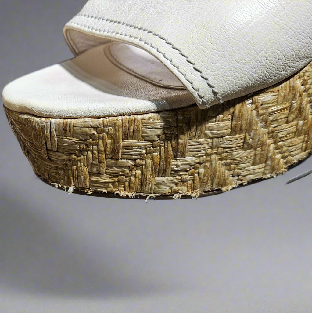Close-up of a sandal with a textured sole on a clear stand.