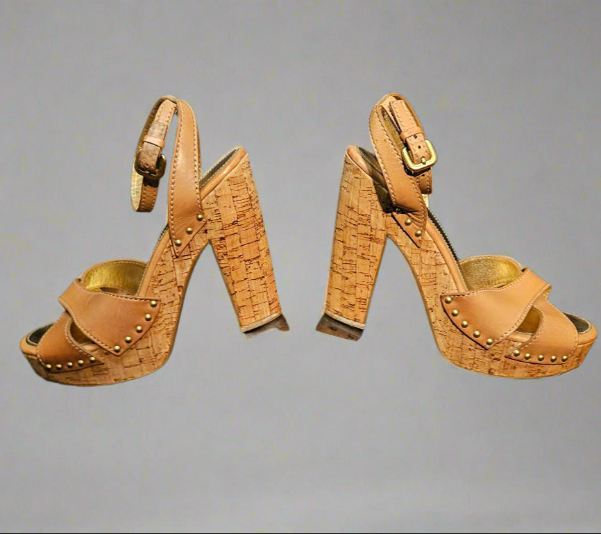 Pair of high-heeled sandals with studded details on a black background