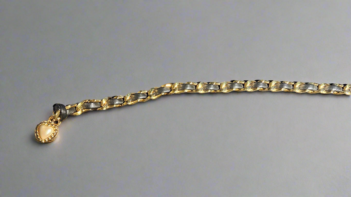 Gold chain belt with a heart-shaped charm on a gray background