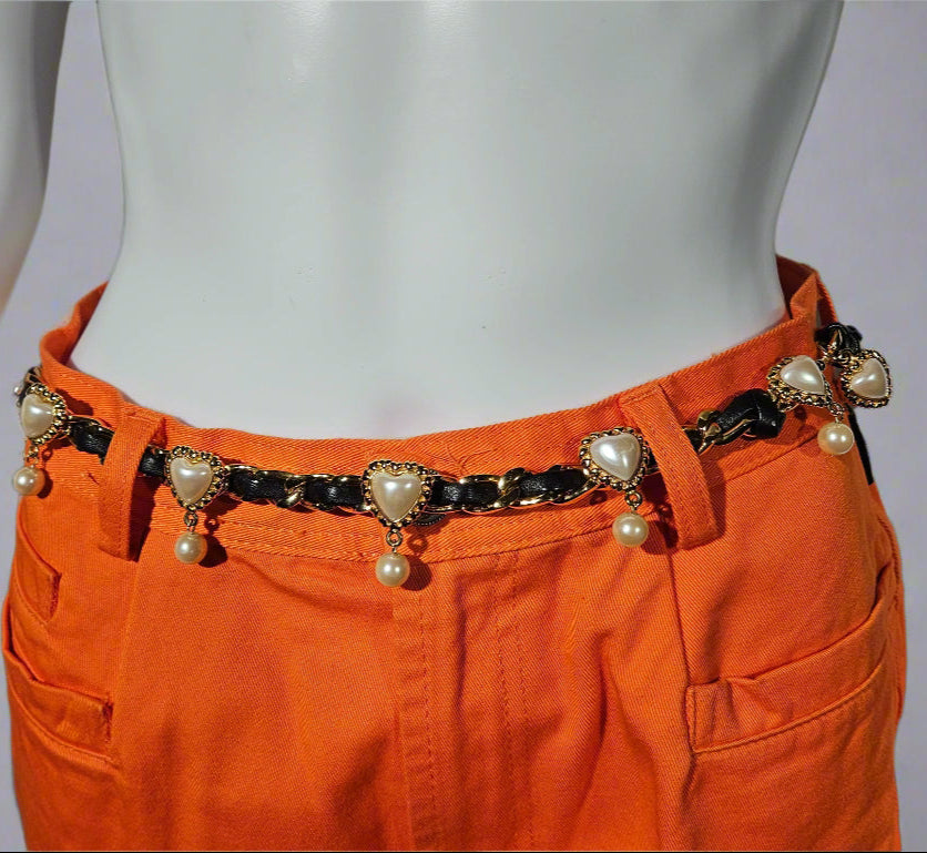 Orange pants with a decorative belt on a mannequin against a neutral background