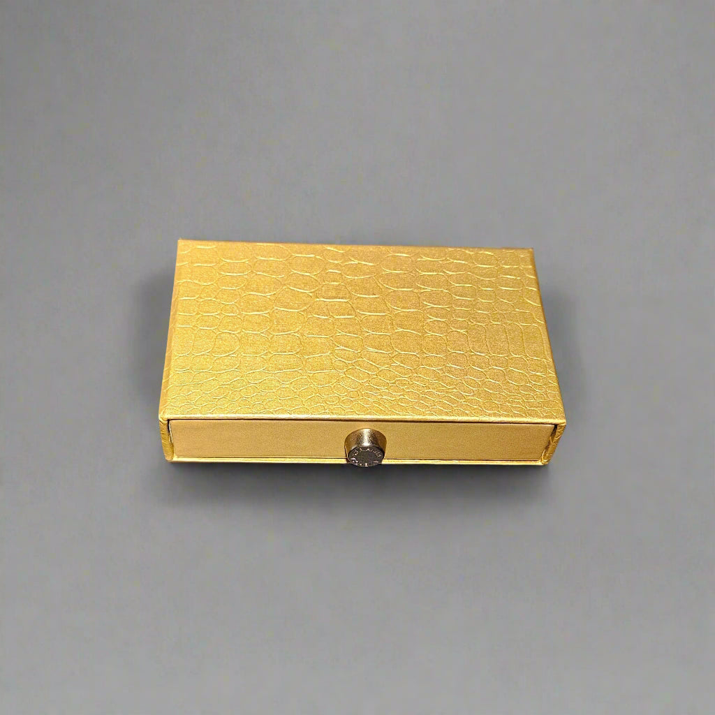Gold textured rectangular box with a metallic clasp on a gray background
