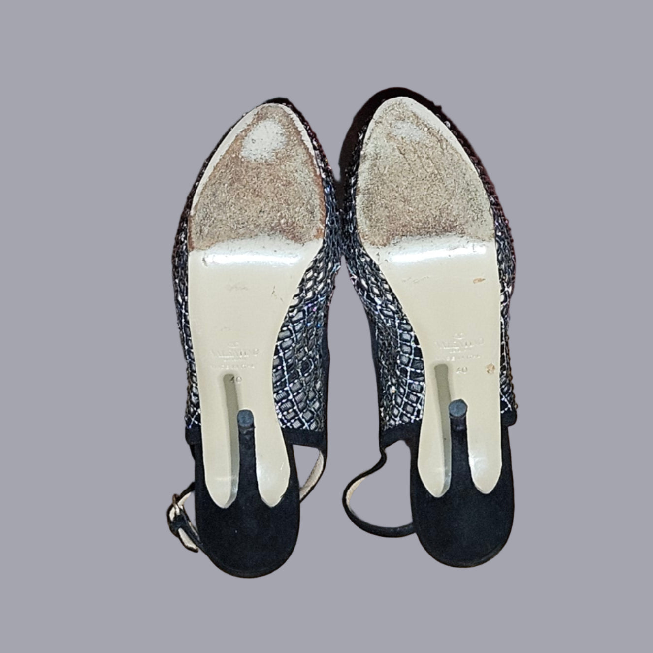 Pair of black shoes with white soles on a floor.