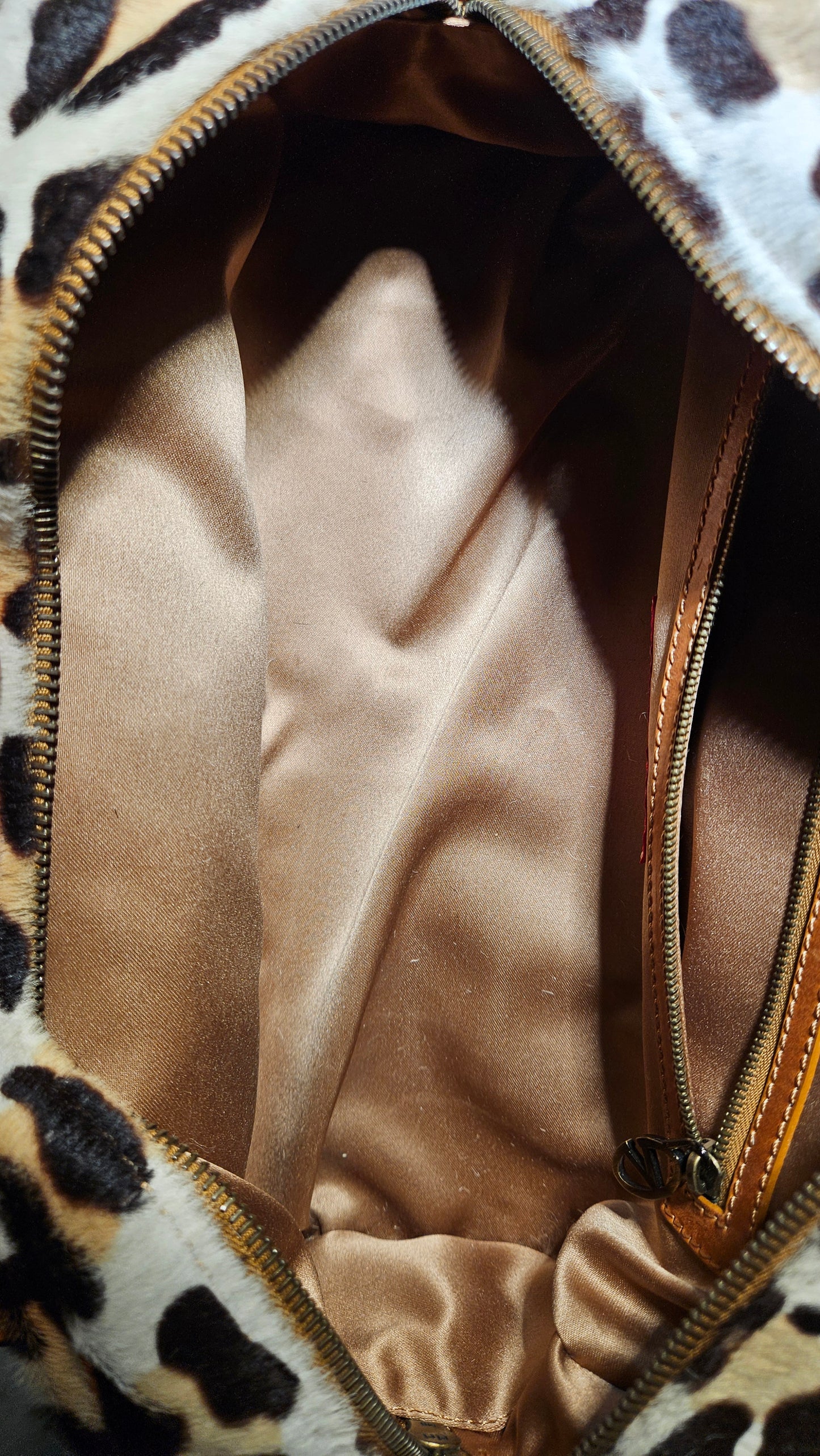Leopard print handbag with a gold zipper, showing the interior.