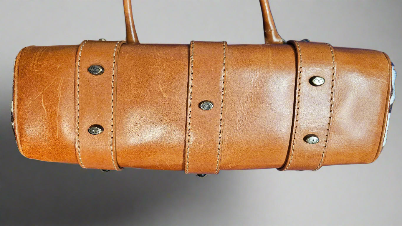 Brown leather bag with visible stitching on a gray background