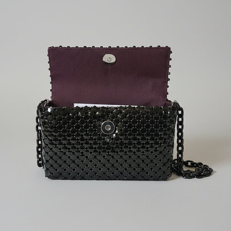 Black beaded handbag with a chain strap on a light gray background