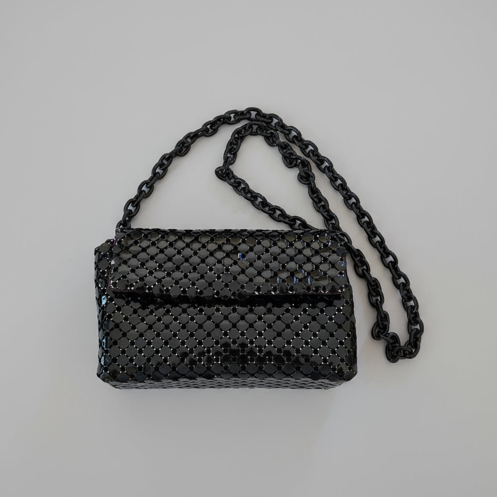 Black mesh handbag with chain strap on a light gray background