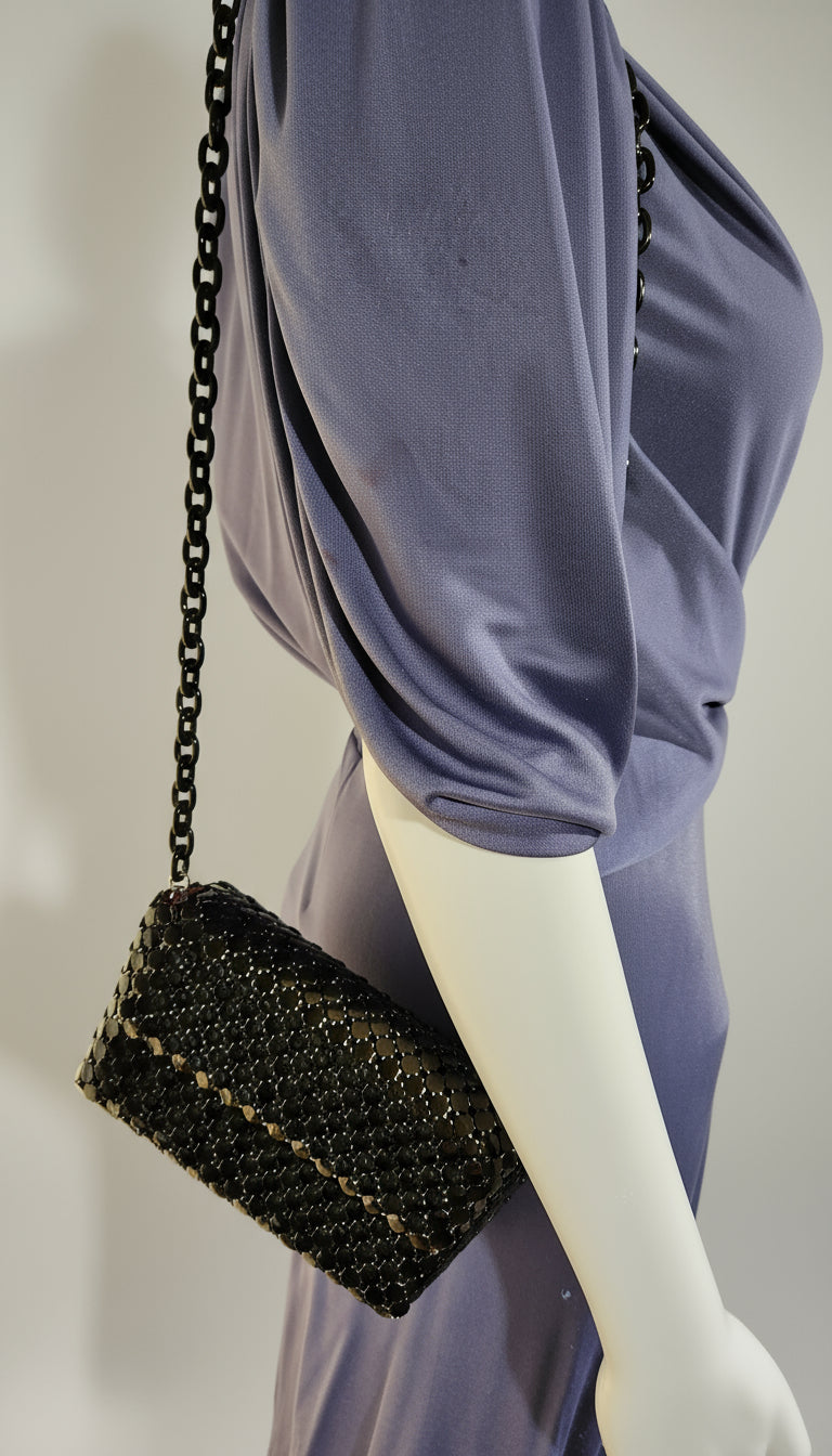 Black beaded handbag on a mannequin with a light purple garment in the background