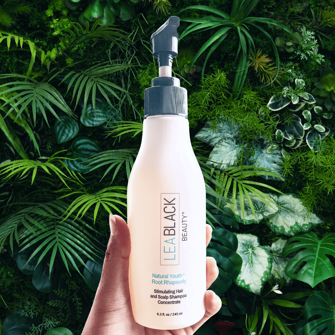 Hand holding Natural Youth Root Rhapsody Shampoo bottle