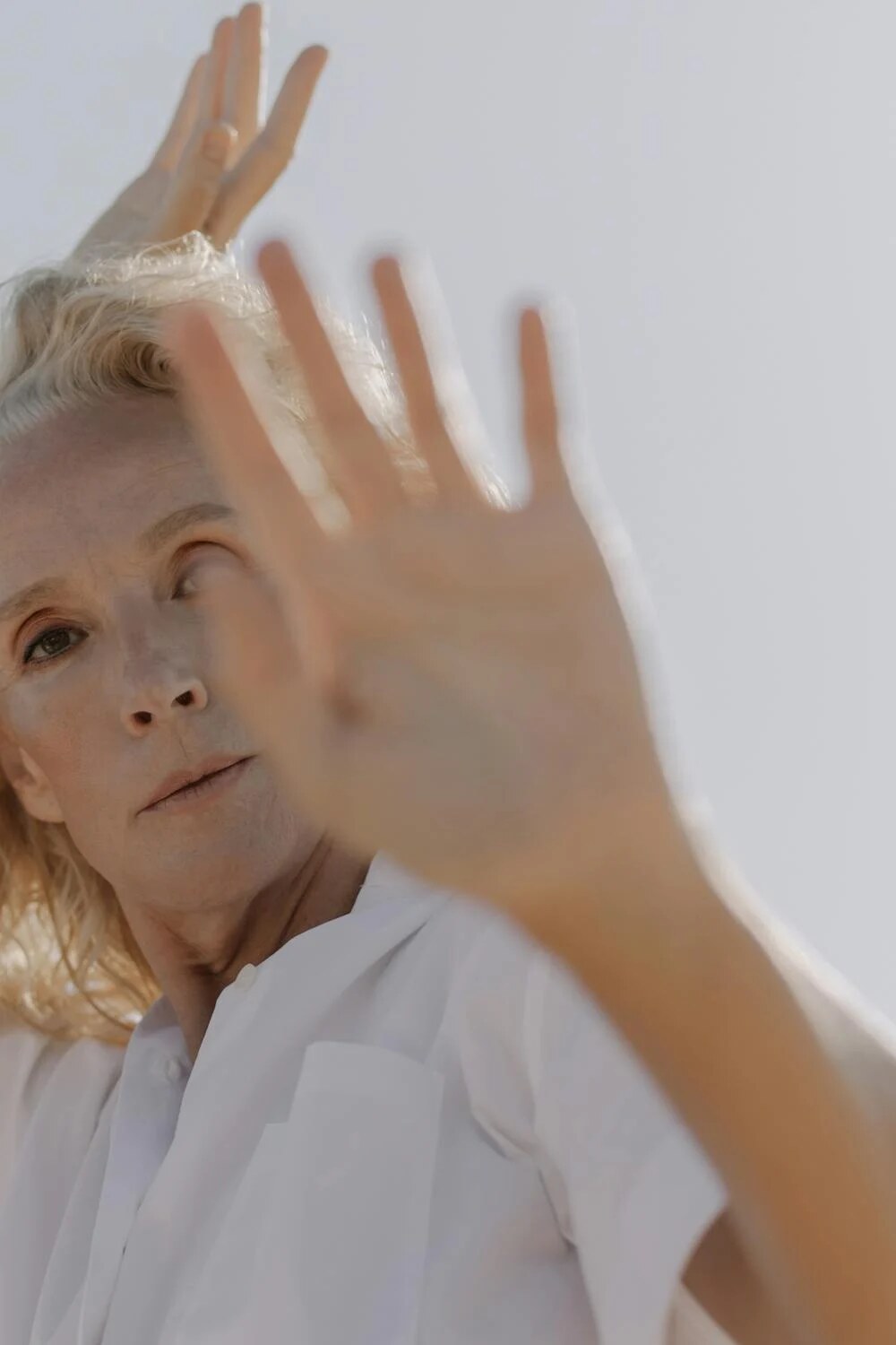 a blonde woman with her hand up in the sunlight