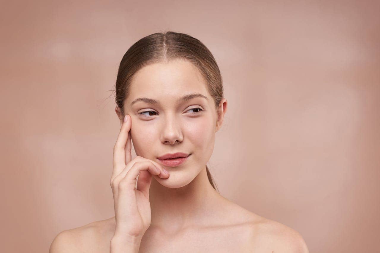 A woman with clear skin holding her face