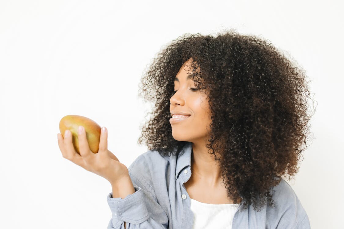 Woman with glowing skin holding a mango