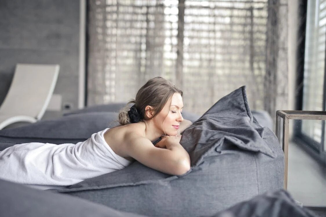 A woman in a white towel relaxing in bed