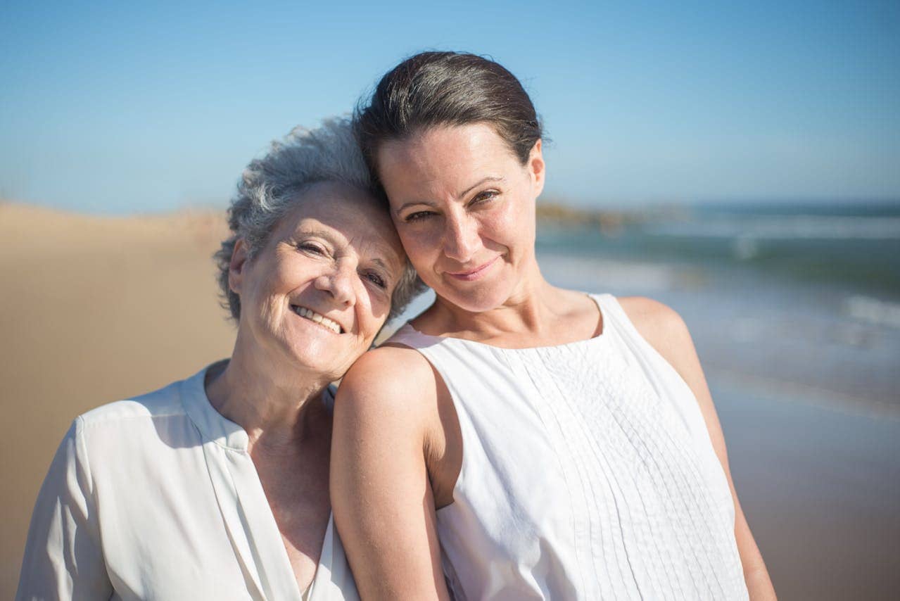 A middle-aged woman and an elderly woman smiling at the beach