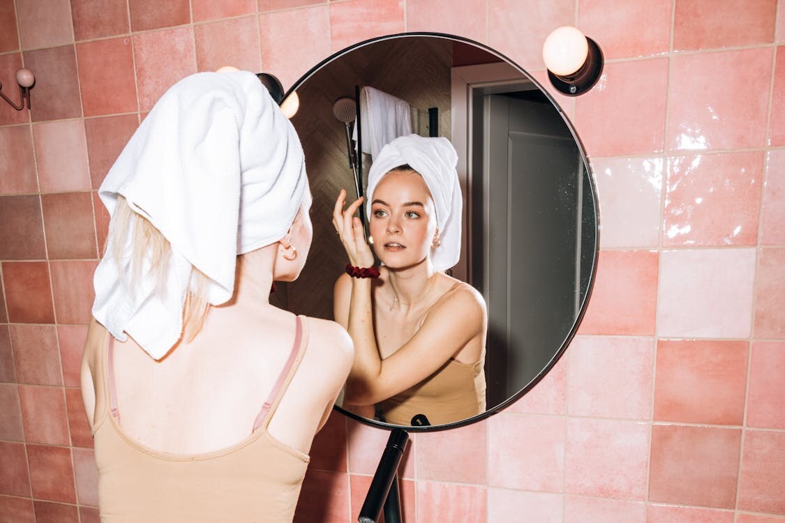 Woman doing a simple skincare routine in front of a mirror